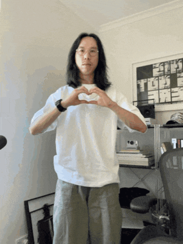 a man in a white shirt making a heart shape