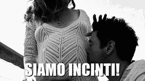 a man is kissing a pregnant woman 's belly .