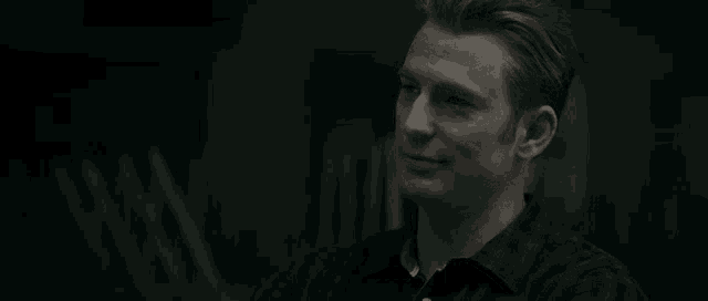 a close up of a man 's face in a dark room smiling .