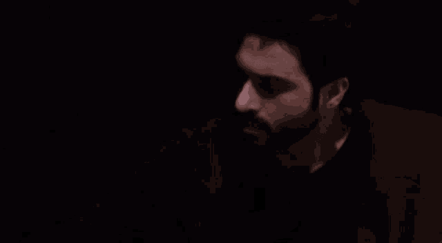 a man with a beard is looking at the camera with a purple background