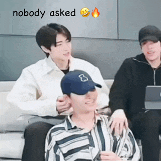 a group of young men are sitting on a couch . one of the men is wearing a baseball cap .