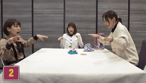 three women are sitting at a table with the number 2 on the table