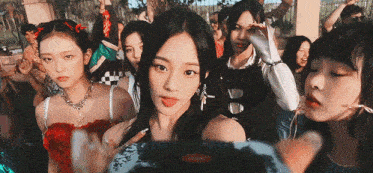 a group of young girls are standing in a crowd and one of them is wearing a red dress