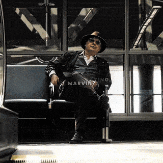 a man wearing a hat and sunglasses is sitting in a chair with the word marvin written on the bottom