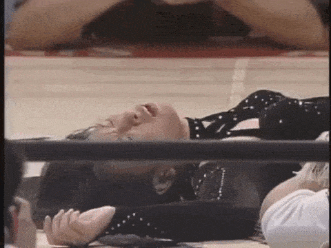 a woman is laying on the ground in a wrestling ring with her eyes closed .