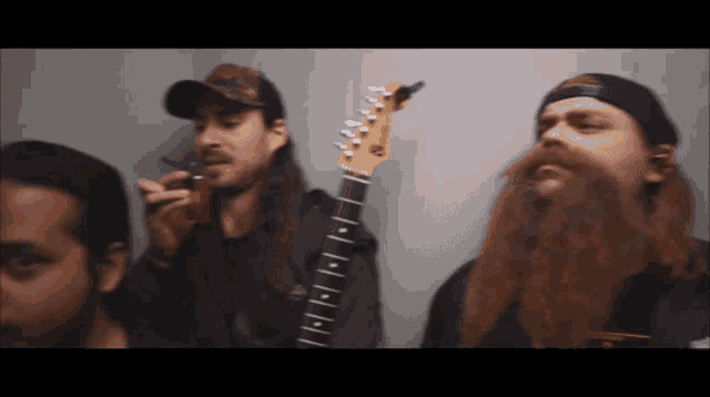 a man with a beard is holding a guitar with the letters e on the neck