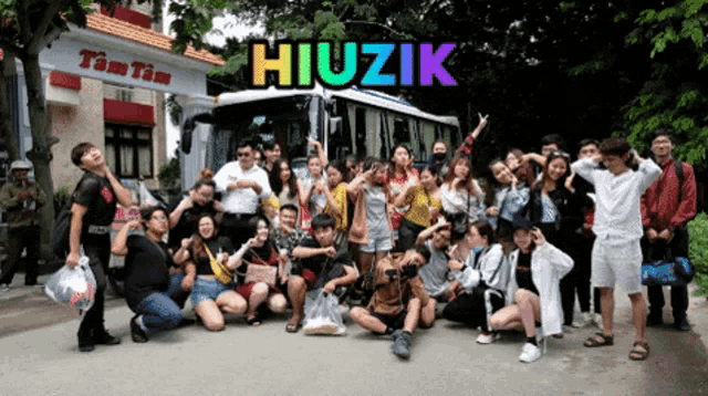 a group of people posing in front of a bus that says hiuzik on the top