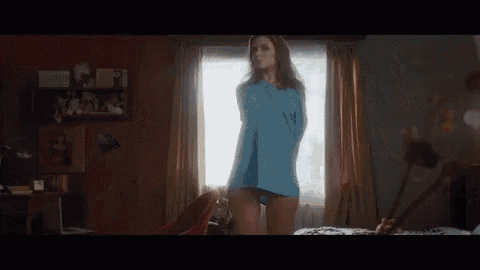a woman in a blue shirt is standing in front of a mirror .