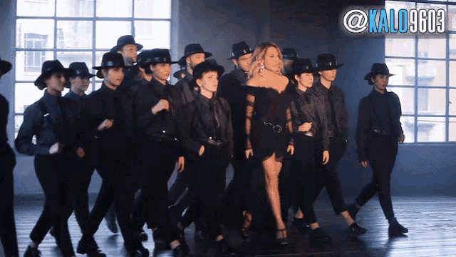 a woman in a black dress is surrounded by a group of men in black suits and hats