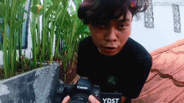 a young man is holding a canon camera