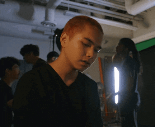 a man in a black shirt with red hair looks down