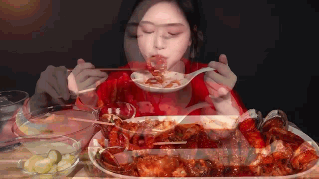 a woman in a red shirt is eating a plate of food with a spoon