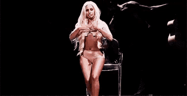 a woman in a bikini is standing on a stage with her arms outstretched in front of a black bull .