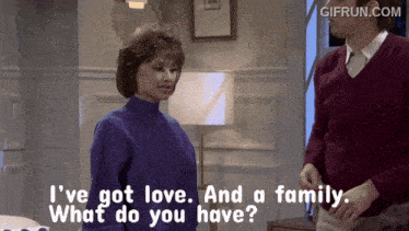 a woman in a purple sweater talks to a man in a red sweater