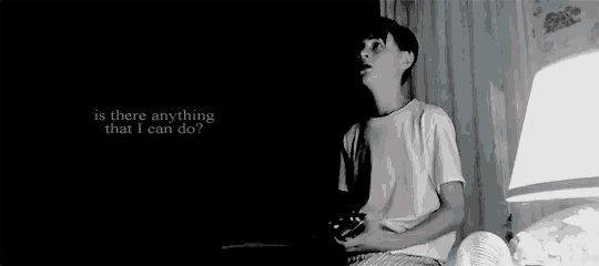 a young boy is sitting on a bed playing a video game with a controller .