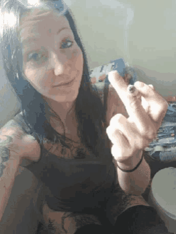 a woman is smoking a cigarette and making a middle finger sign
