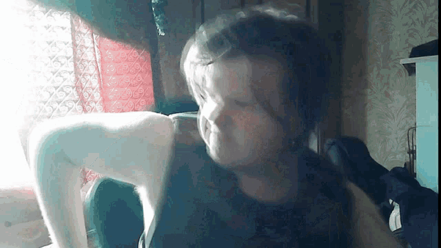 a woman is sitting in front of a window with her eyes closed .