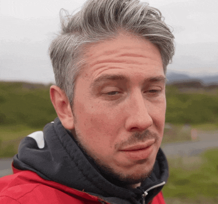 a man with gray hair is wearing a red jacket and a black hoodie