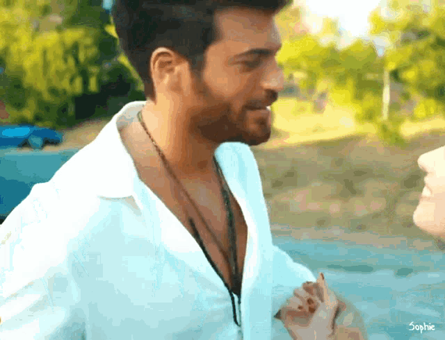 a man in a white shirt is holding a woman 's hand and the name sophie is on the bottom right