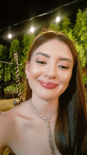 a woman wearing a necklace and earrings is smiling for the camera