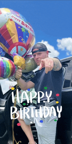 a man is pointing at the camera while holding a balloon that says happy birthday