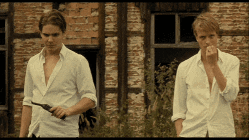 two men in white shirts standing in front of a brick building