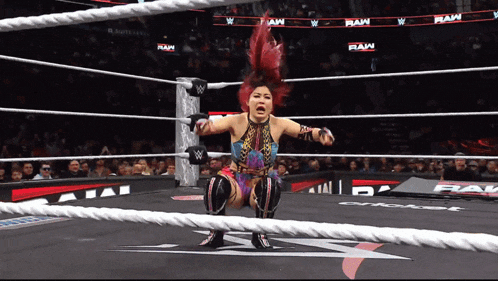 a female wrestler is squatting in a wrestling ring with the word raw behind her