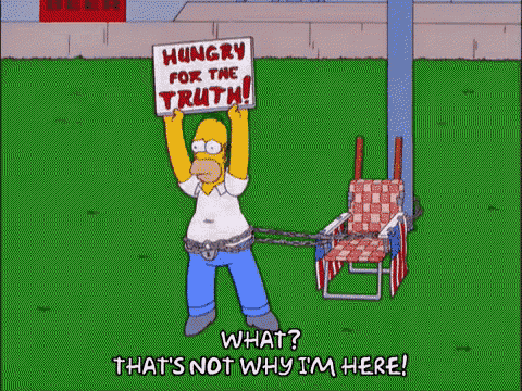 homer simpson is chained to a beach chair and holding a sign that says `` hungry for the truth '' .