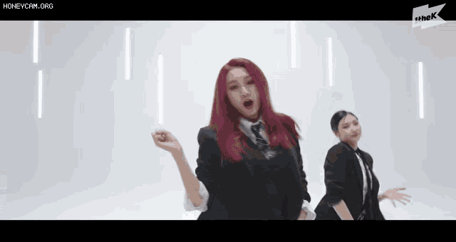 two women with red hair are dancing in front of a white background