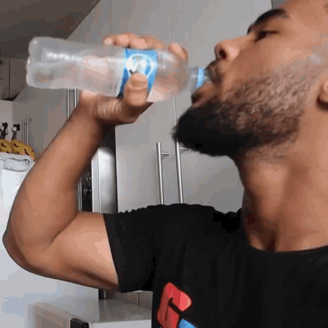 a man drinking water from a bottle with a blue label that says ' aquafina ' on it