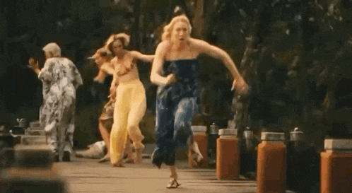 two women in yellow pants are running down a sidewalk in a park .