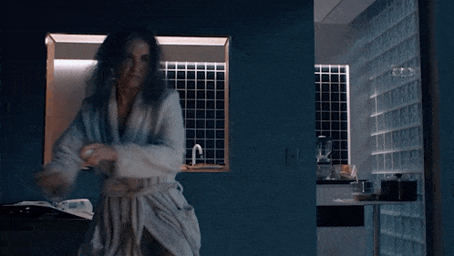 a woman in a bathrobe dancing in a bathroom