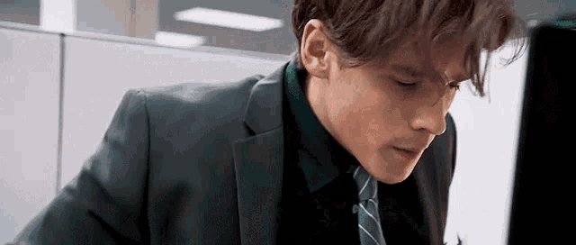 a man in a suit and tie is sitting at a desk in an office .