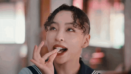 a woman with curly hair is eating a piece of food