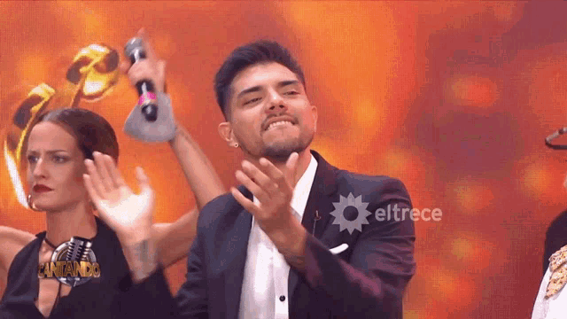 a man in a suit holds a microphone in front of eltrece