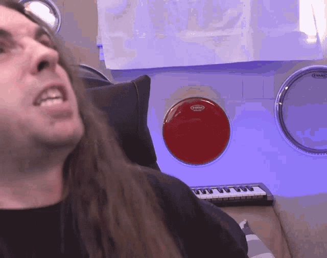 a man with long hair is sitting in front of a drum that says evans