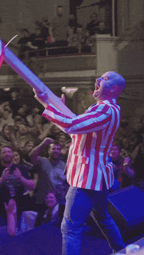 a man in an american flag jacket stands in front of a crowd of people