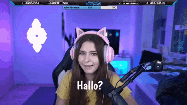a girl wearing pink headphones says hallo on a screen