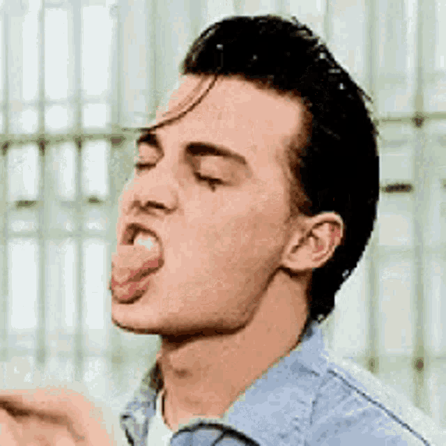 a man is sticking his tongue out while wearing a blue shirt and a white shirt .