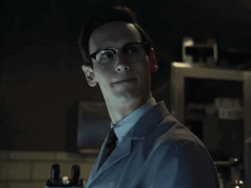 a man wearing glasses and a lab coat smiles