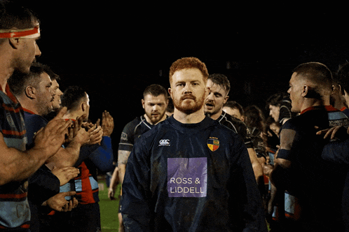a man in a ross & liddell shirt stands in a crowd