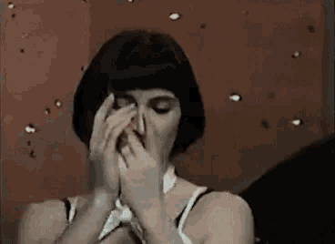 a woman is covering her face with her hands in a room .