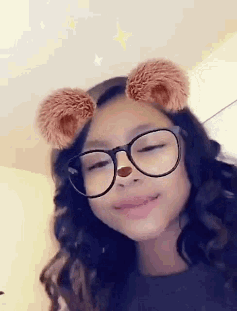 a young girl wearing glasses and a teddy bear face filter .