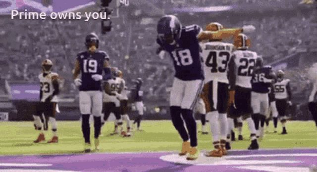 a football player with the number 18 on his jersey is jumping in the air .