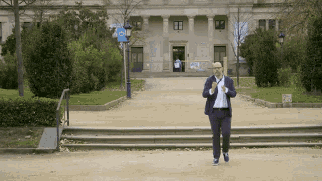 a man in a suit is running in front of a building with a sign on it that says ' a ' on it