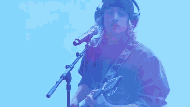 a man singing into a microphone while holding a guitar