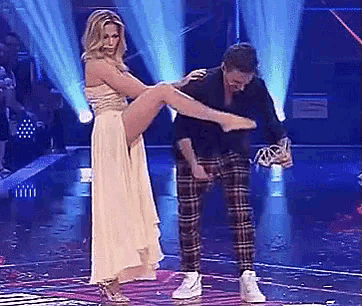a man is holding a woman 's leg while she dances on a stage