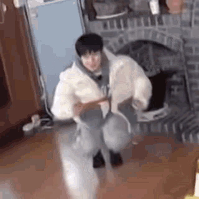 a man is kneeling on the floor in a living room holding a book .