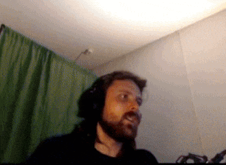 a man with long hair and a beard is wearing headphones in front of a green curtain
