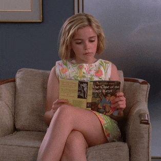 a woman is sitting on a couch reading a book called the clue of the black keys